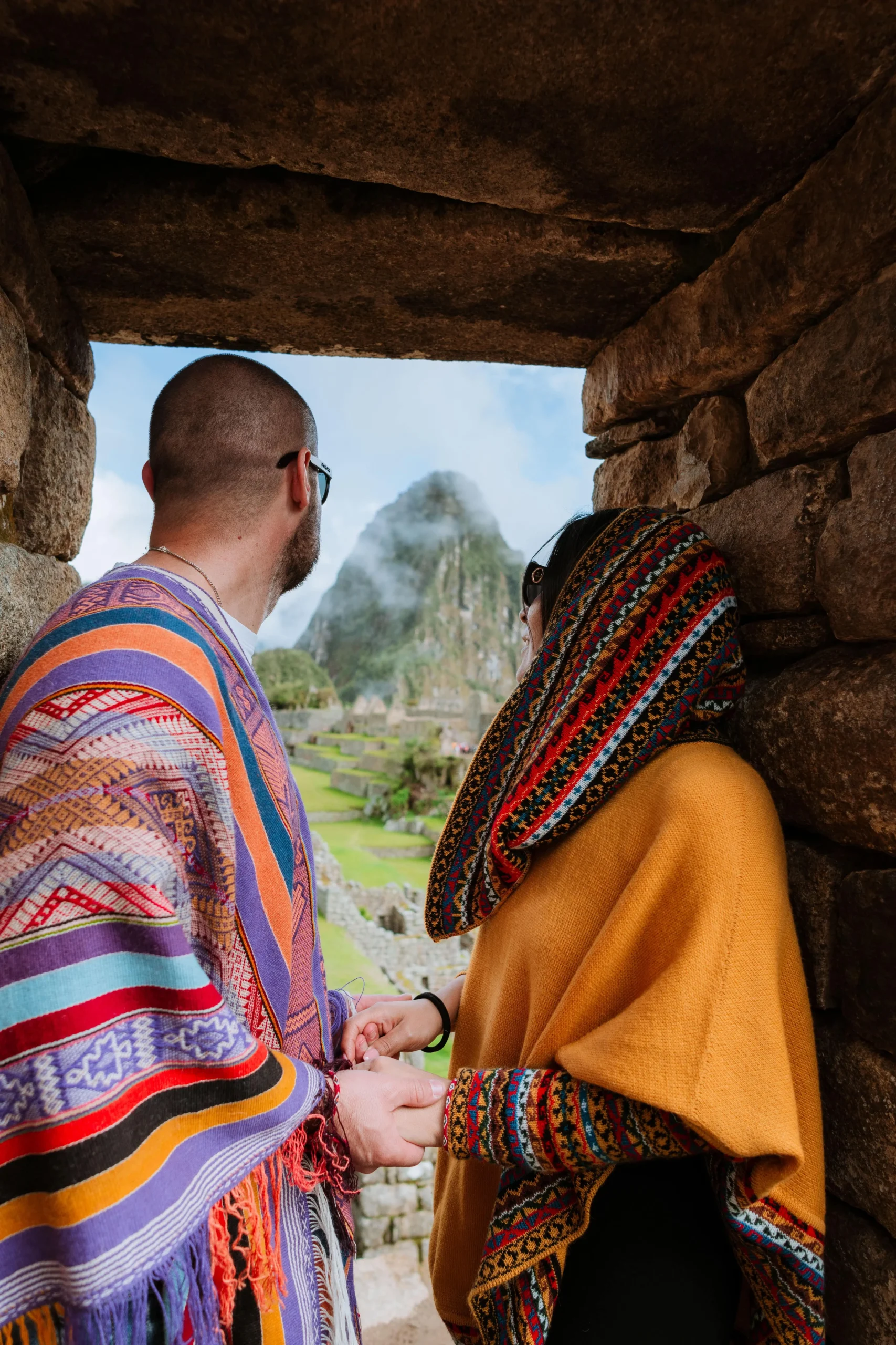 Couple admiring the view through a stone doorway at Machu Picchu.